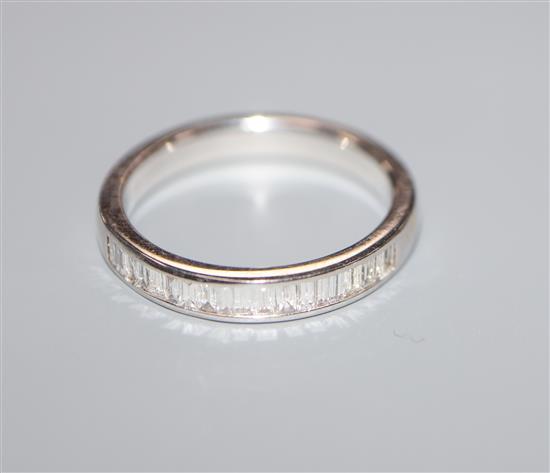 A modern 18ct white gold and eighteen stone baguette cut diamond set half hoop ring, size M.